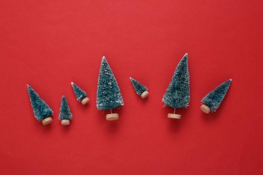 Kırmızı arka planda mini Noel ağaçları. Yeni yıl ya da Noel arkaplanı