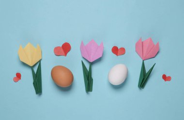 Origami laleleri, mavi arka planda yumurtalar ve kalpler. Bahar, Paskalya konsepti