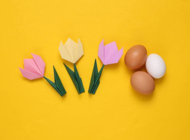 Sarı arka planda Origami laleleri ve yumurtaları. Bahar, Paskalya konsepti