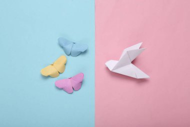 Origami kelebeklerinin bileşimi ve mavi pastel arka planda güvercin.