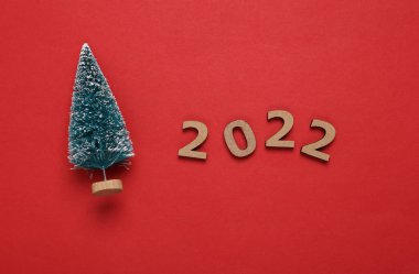 2022 ve kırmızı arka planda mini noel ağacı. Noel, yeni yıl kompozisyonu