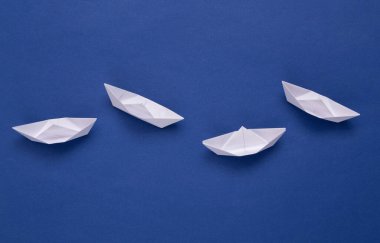 Mavi arka planda beyaz kağıt tekneler