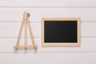 Küçük boş tebeşir tahtası ve üç ayaklı beyaz tahta masa.