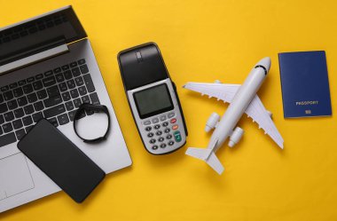 Ödeme terminali ve seyahat aksesuarları, sarı arka planda dizüstü bilgisayar. Düz yatıyordu