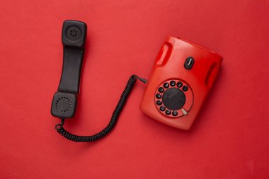 Kırmızı arka planda eski moda döner telefon. Üst görünüm