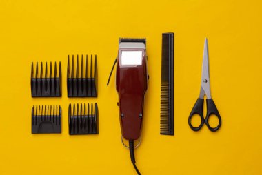 Saç kesim makinesi, makas ve sarı arka planda tarak. Berber dükkanı. Saç makası. Üst Manzara. Düz yatıyordu