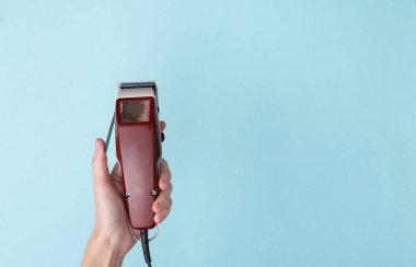 Saç stili için el ele tutuşma makinesi, mavi arka planda saç makası. Berber dükkanı. Boşluğu kopyala