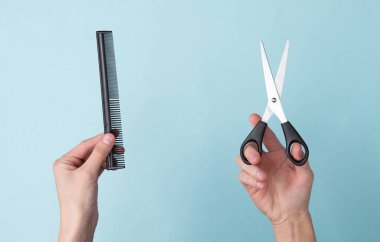 Mavi arka planda el yapımı makas ve saç fırçası. Saç kesimi, saç bakımı, berber dükkanı için hazır.