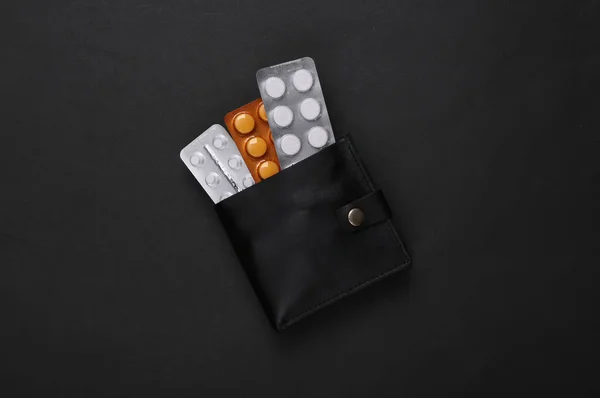 Wallet with blister of pills on black background
