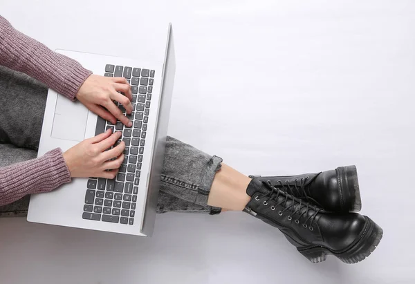 这个女人在白色背景上使用笔记本电脑 女腿穿牛仔裤和靴子 在线工作 顶部视图 — 图库照片