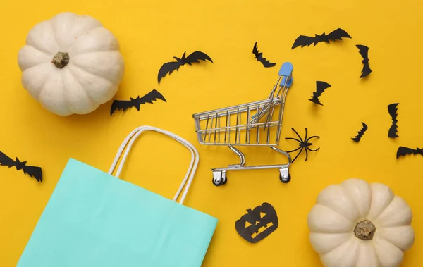 Shopping paper bag with Halloween decor on yellow background. Halloween shopping. Top view