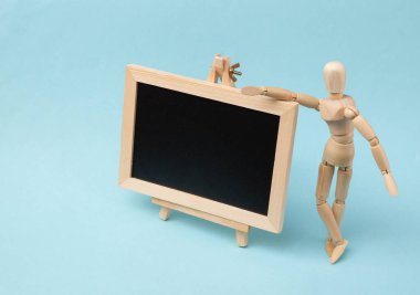 Mini tebeşir tahtası ve mavi arka planda tahta kukla. Öğrenim, iş, eğitim, okul kavramı