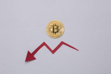 Bitcoin ve düşen ok gri arka planda. Kripto para birimi. Bitcoin değeri düşüyor