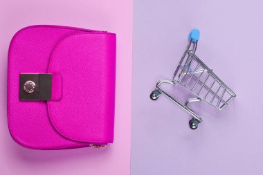 Alışverişkolik minimalist kavram. İki çanta, pastel arka planda küçük bir alışveriş arabası. Üst görünüm