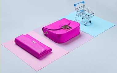 Alışverişkolik minimalist kavram. Çanta, çanta, pastel arka planda mini alışveriş arabası. Yan görünüm