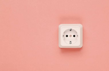 Mercan rengi arka planda beyaz plastik prizler. Kopya alanı olan duvar. Minimalizm