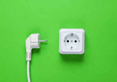 Beyaz plastik priz ve yeşil arka planda elektrik prizi. Üst görünüm