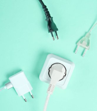Elektrik bağımlılığı kavramı. Mavi arkaplanda elektrik prizlerinin yanında bir sürü elektrik prizi var