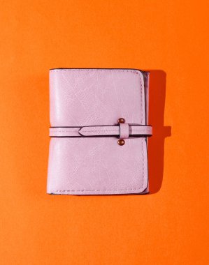 Turuncu arka planda pembe deri cüzdan. Üst görünüm