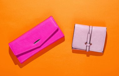 Turuncu arka planda pembe ve kırmızı deri cüzdanlar. Üst görünüm