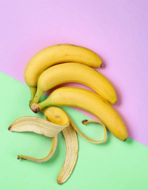 Minimalizm meyve konsepti. Pastel arka planda muz ve muz kabuğu var. Üst görünüm