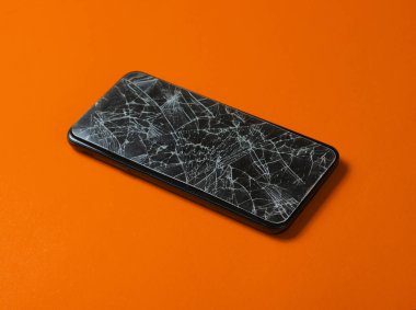 Turuncu arka planda kırık camlı akıllı telefon..