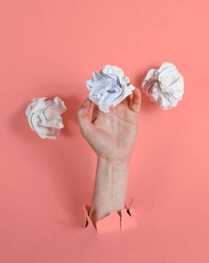 Kadın eli, buruşmuş kağıt toplarını yırtılmış pembe kağıtlarla tutuyor. Minimalist fikir işi konsepti