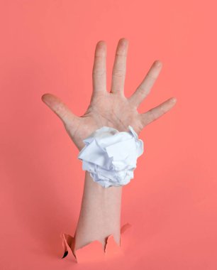 Kadın eli, buruşmuş kağıt topunu yırtık pembe kağıt arka planına fırlatıyor. Asgari fikir kavramı