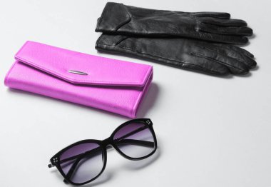 Mor deri cüzdan, güneş gözlüğü, beyaz arka planda eldivenler.