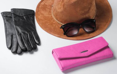 Kadın moda aksesuarları. Mor deri cüzdan, güneş gözlüğü, beyaz arka planda eldivenler.