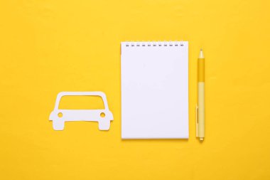 Kağıt kesiği araba ve sarı arka planda defter. 