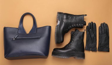 Şık deri çizmeler, bej arka planda çanta ve eldivenler. Kadın sonbahar aksesuarları. Üst Manzara. düz yat