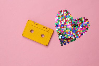 Pembe arka planda ses kaseti ve kalp şeklinde konfeti.