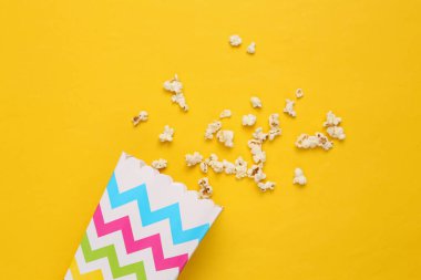 Sarı arka planda lezzetli tuzlu patlamış mısırlı kova. Fast food ve film atıştırmalığı.