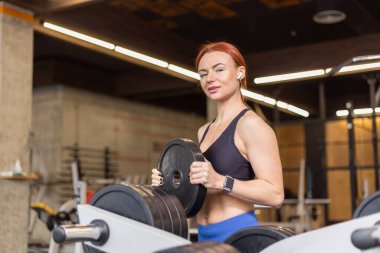 Spor salonunda halter diski tutan zinde bir kadın.