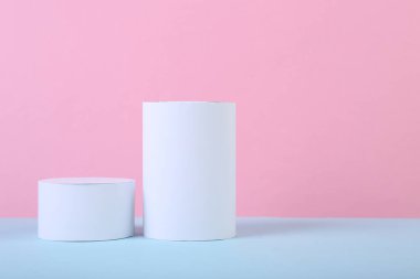 Geometrik şekillerin minimalist arka planı. Mavi, pembe renkli arka planda iki silindir.