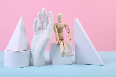 Geometrik şekiller, ahşap kukla ve mavi-pembe renkli arka plan. Farklı geometrik nesnelerin bileşimi. Sanat kavramı. Soyut arkaplan, minimalizm