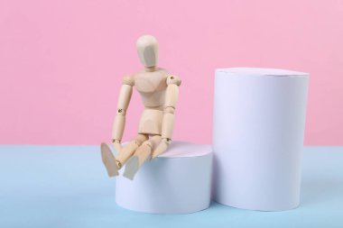 Geometrik şekilli mavi-pembe arka planda tahta bir kukla..