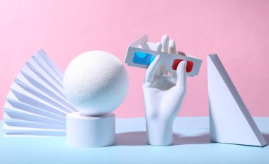 Manken el, mavi pastel arka planda stereoskopik üç boyutlu gözlük ve geometrik şekiller bulundurur. Sanat kavramı. Minimalizm
