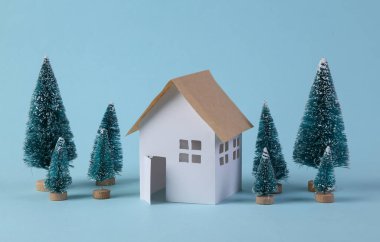 Ev modeli ve mavi arka planda bir Noel ağacı..