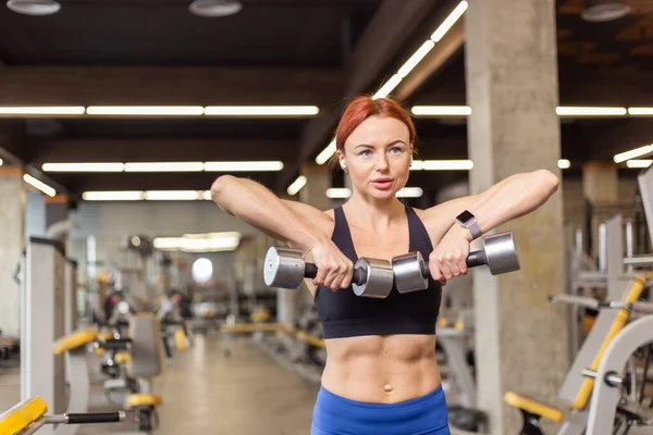 Aantrekkelijke Roodharige Fitnessvrouw Traint Schouderspieren Met Halters Een Moderne Fitnessruimte — Stockfoto