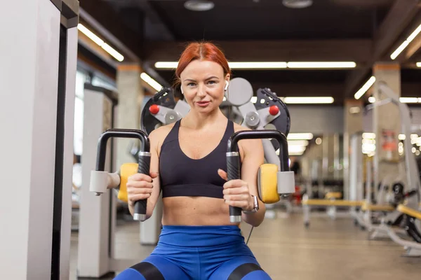 Muscular Fit Rudowłosa Kobieta Trenuje Mięśnie Ramion Maszynie Ćwiczeń Siłowni — Zdjęcie stockowe