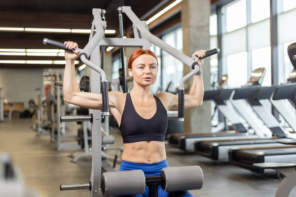 Muscular Fit Rudowłosa Kobieta Trenuje Mięśnie Ramion Urządzeniu Ćwiczeń Siłowni — Zdjęcie stockowe