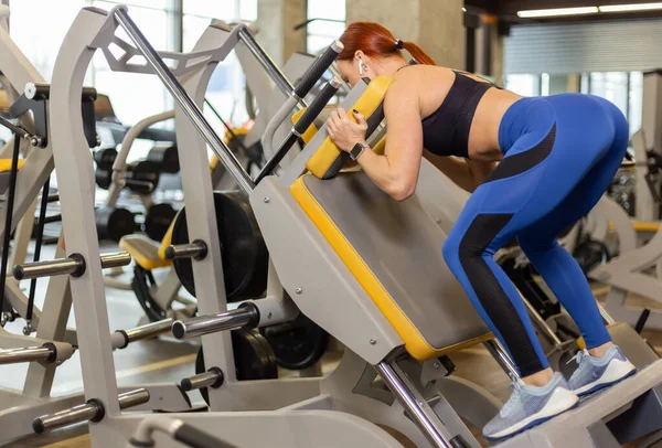 Fit woman practicing back squats in gakk exercise machine