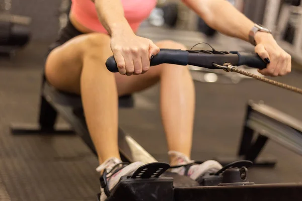 Kızıl saçlı fit kadın modern spor salonunda kürek çekme makinesinde egzersiz yapıyor.