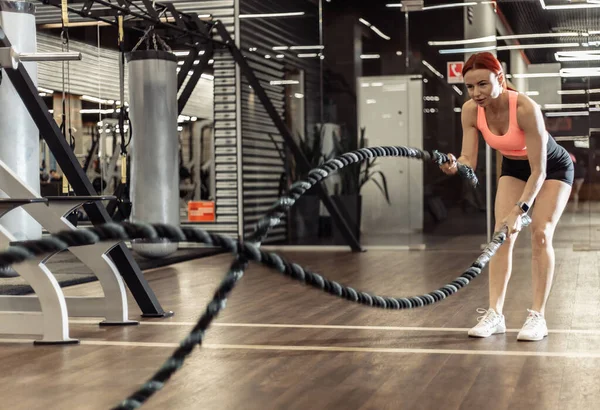 Yoğun idman, savaş halatlarıyla uyumlu bir kadın. Fonksiyonel eğitim