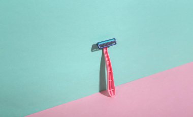 Mavi-pembe arka planda jilet epilatörü. Minimalizm. Moda gölgesi. Yaratıcı düzen. Güzellik konsepti