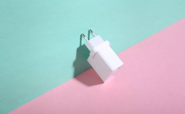 Şarj cihazı mavi-pembe arka planda. Minimalizm. Moda gölgesi. Yaratıcı düzen. Modern aygıtlar