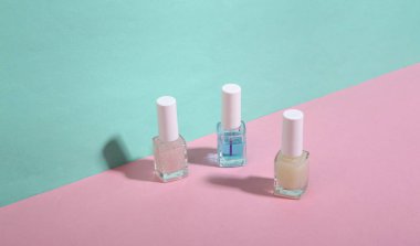 Mavi-pembe arka planda çivi cilası şişeleri. Minimalizm. Moda gölgesi. Yaratıcı düzen. Güzellik hayattır