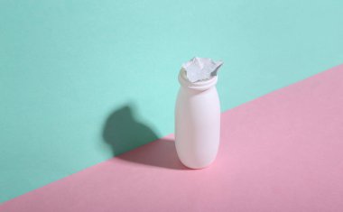 Mavi-pembe arka planda yoğurt şişesi açık. Minimalizm. Moda gölgesi. Yaratıcı yerleşim.